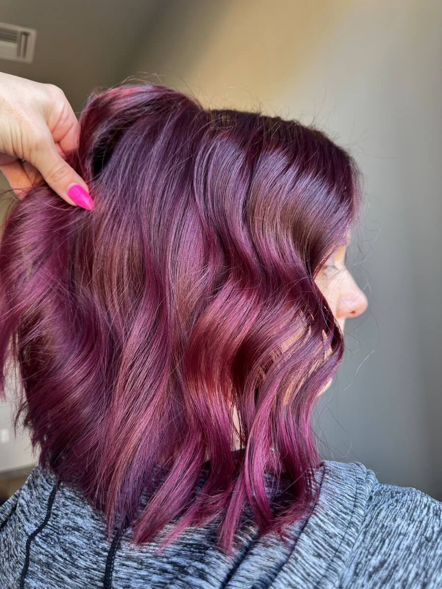 Model with bright red‑violet hair reflecting cool violet undertones and soft, even saturation image by @vividhaircreations