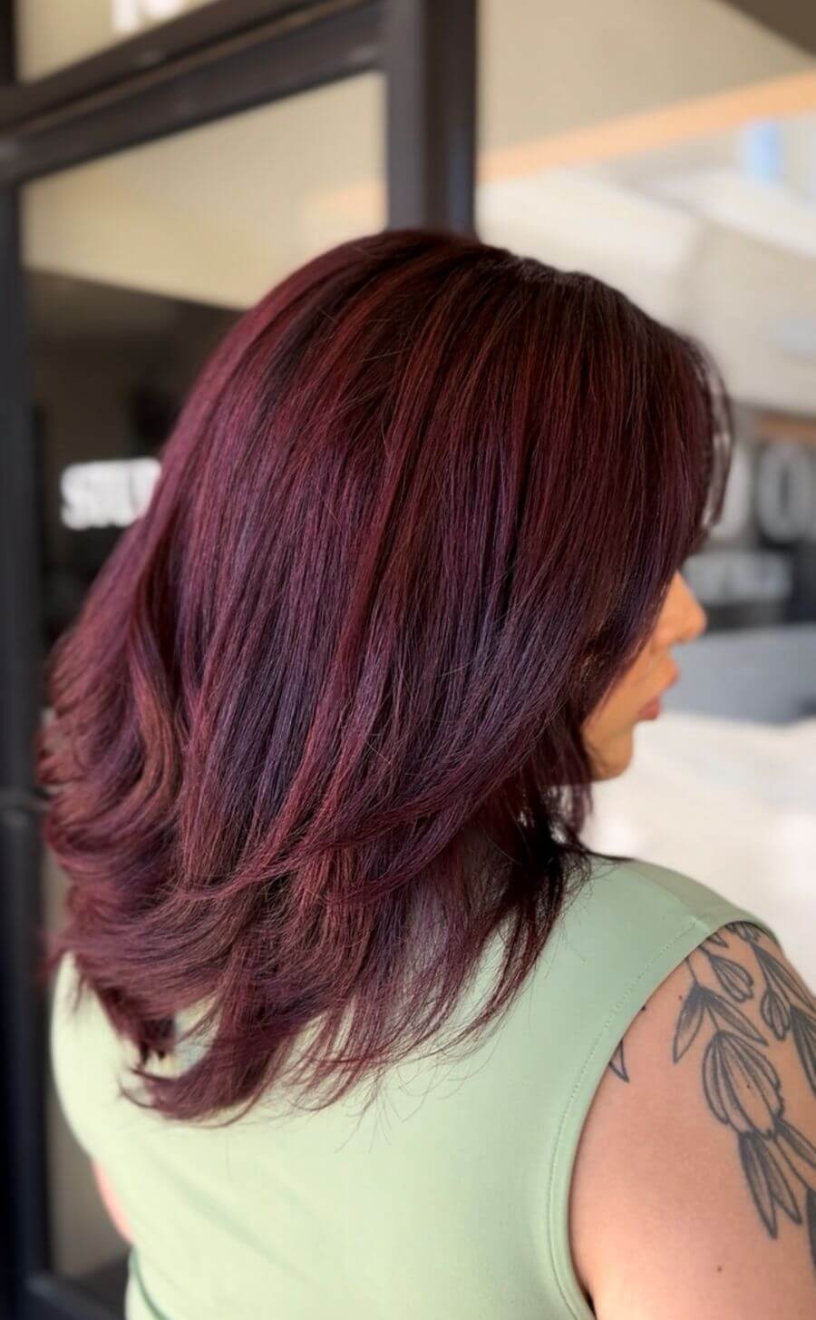 Model with rich red‑violet hair featuring deep berry tones and a glossy finish image by @hairwithhopes