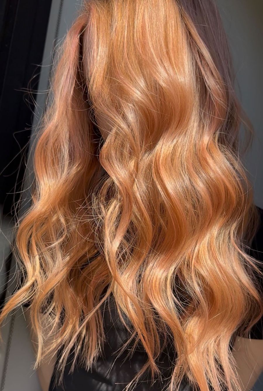 Aperol Spritz-inspired copper hair color with glossy, warm orange tones and sunlit dimension.